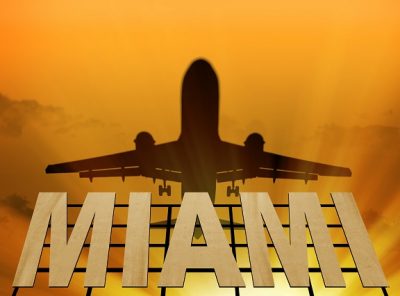 Airplane flying over the sign of Miami at sunset. Signboard of Miami and airplane silhouette (3d-Illustration)